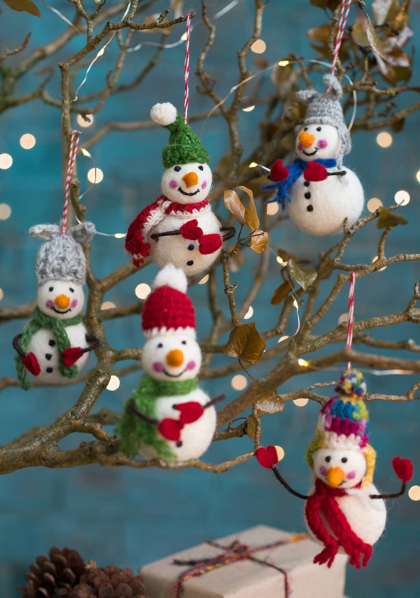 Felted snowman with colourful hat, scarf and bendy arms with mittens on.