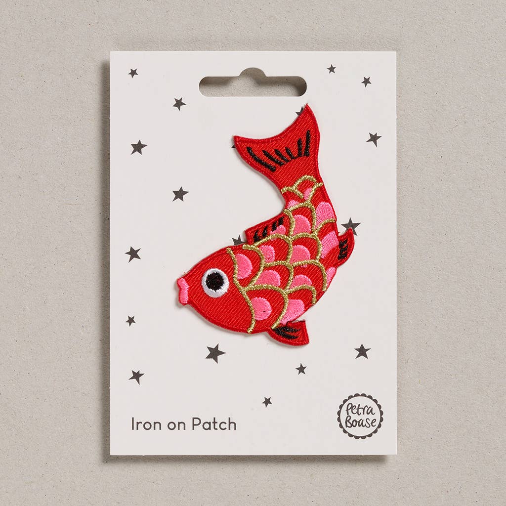 Red fish-shaped iron on patch on a white card with star patterns, branded 'Lotta & Ossie'.