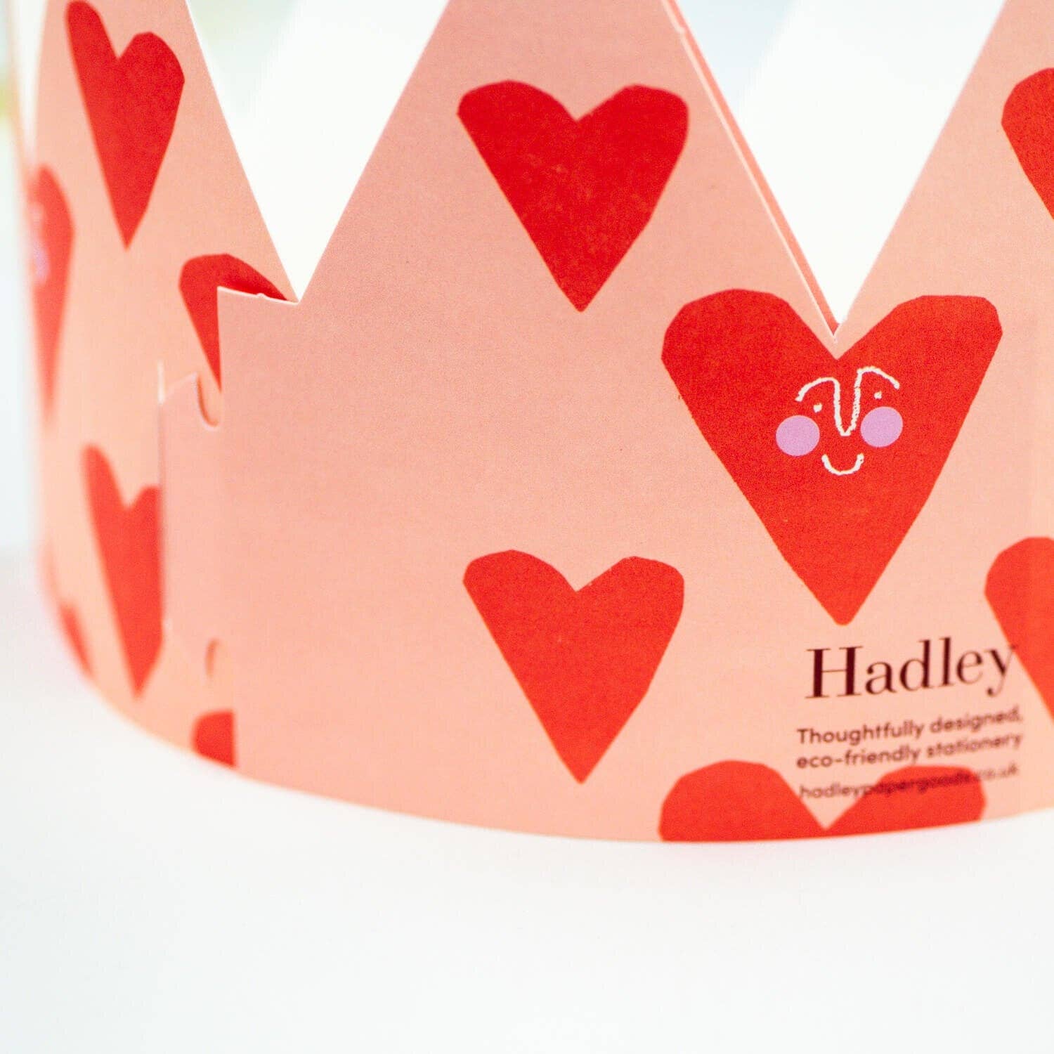 Pink paper crown with red hearts and 'Hadley' branding on a white background