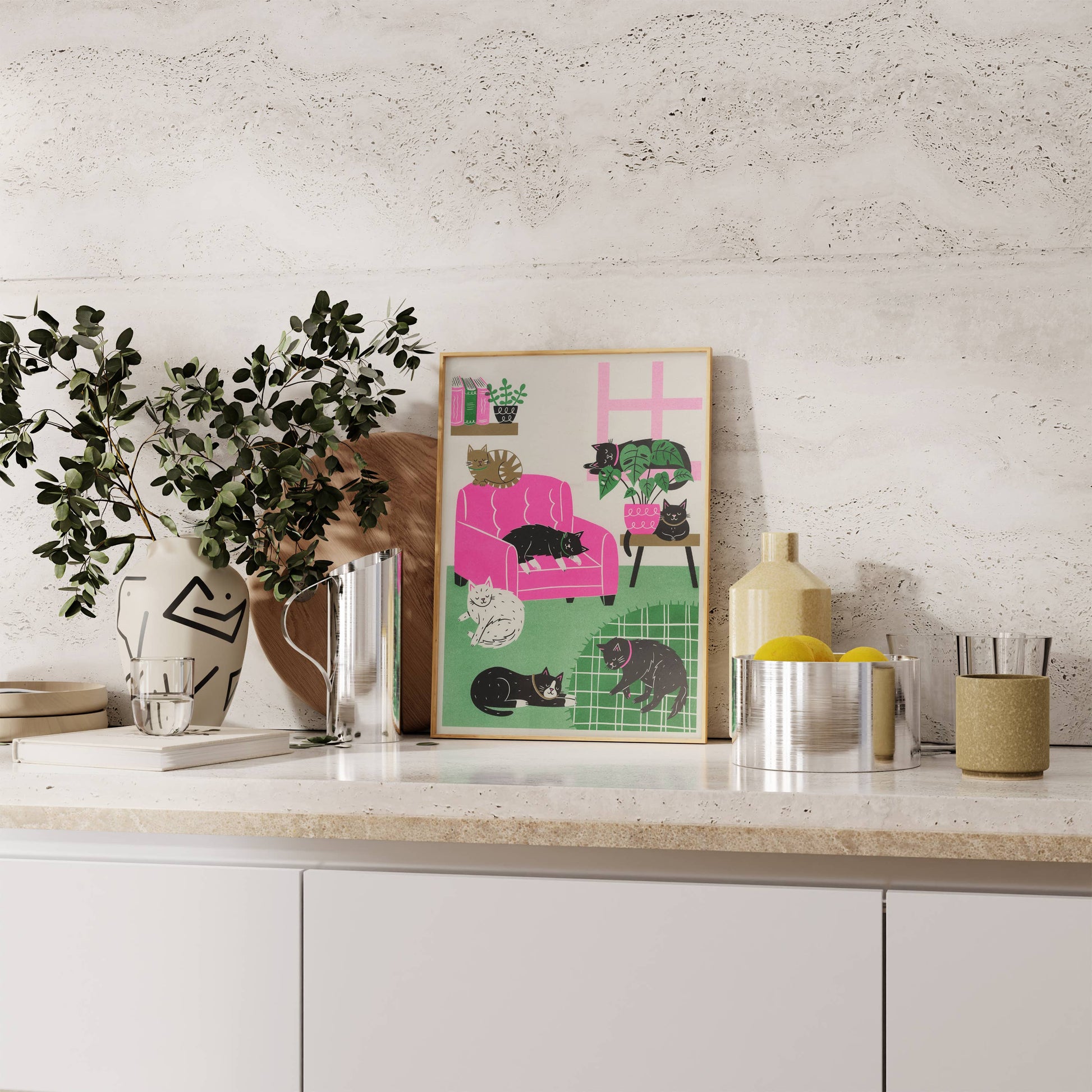 Decorative poster of a pink armchair with cats on a kitchen counter.