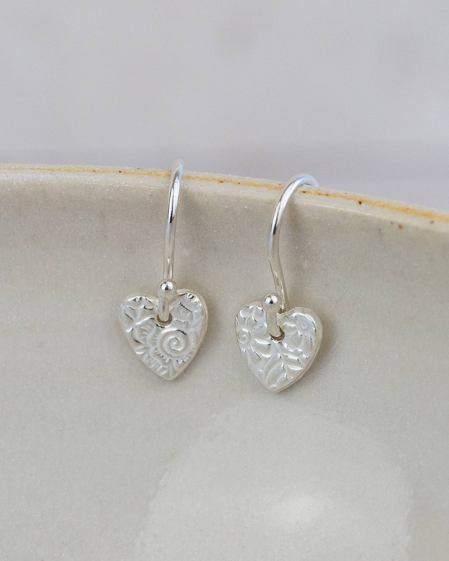 Silver heart-shaped earrings on a white dish