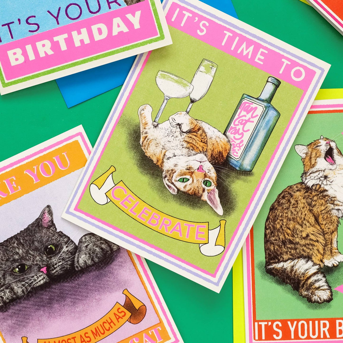Cat-themed birthday cards with colorful designs on a green background