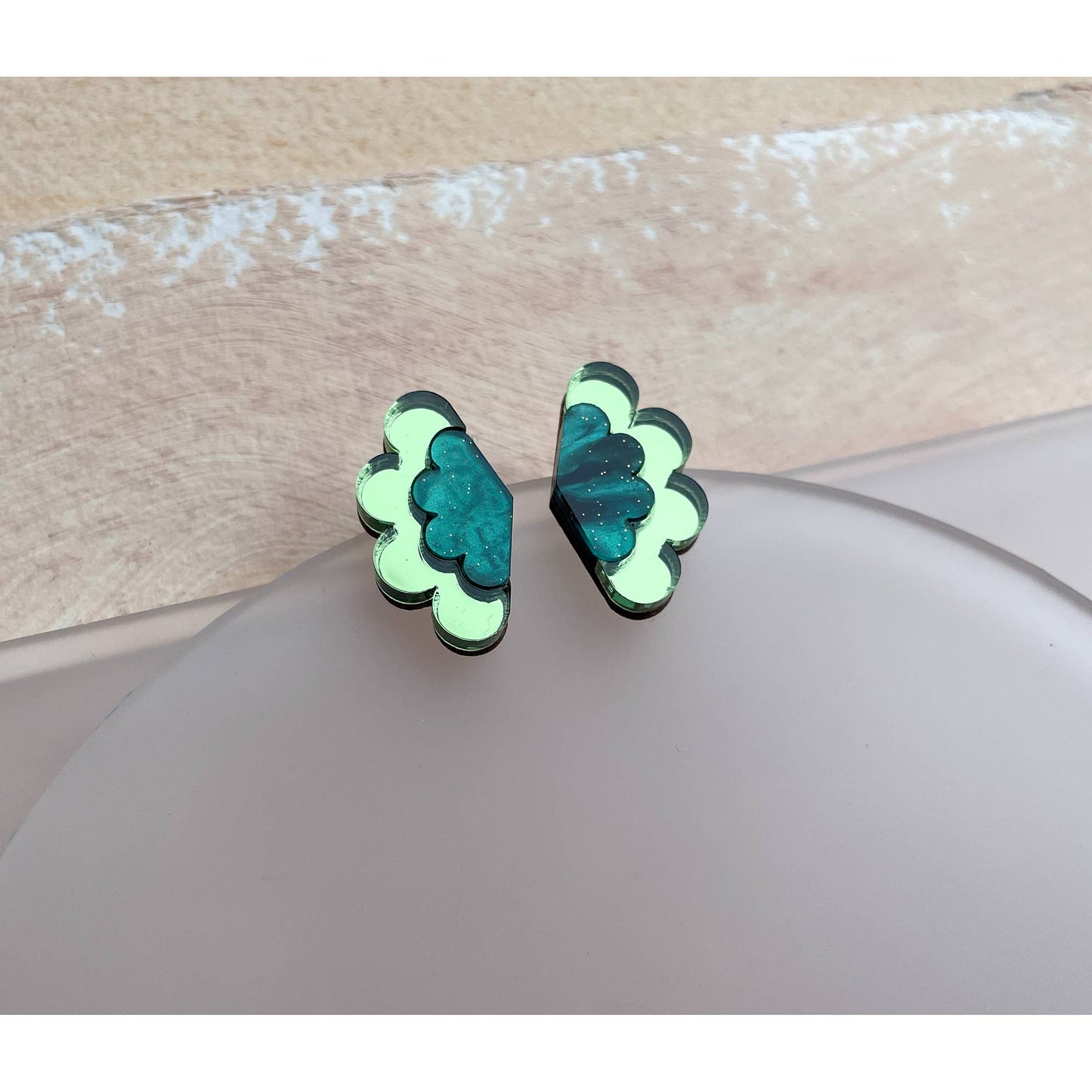 Pair of green butterfly-shaped earrings on a beige surface