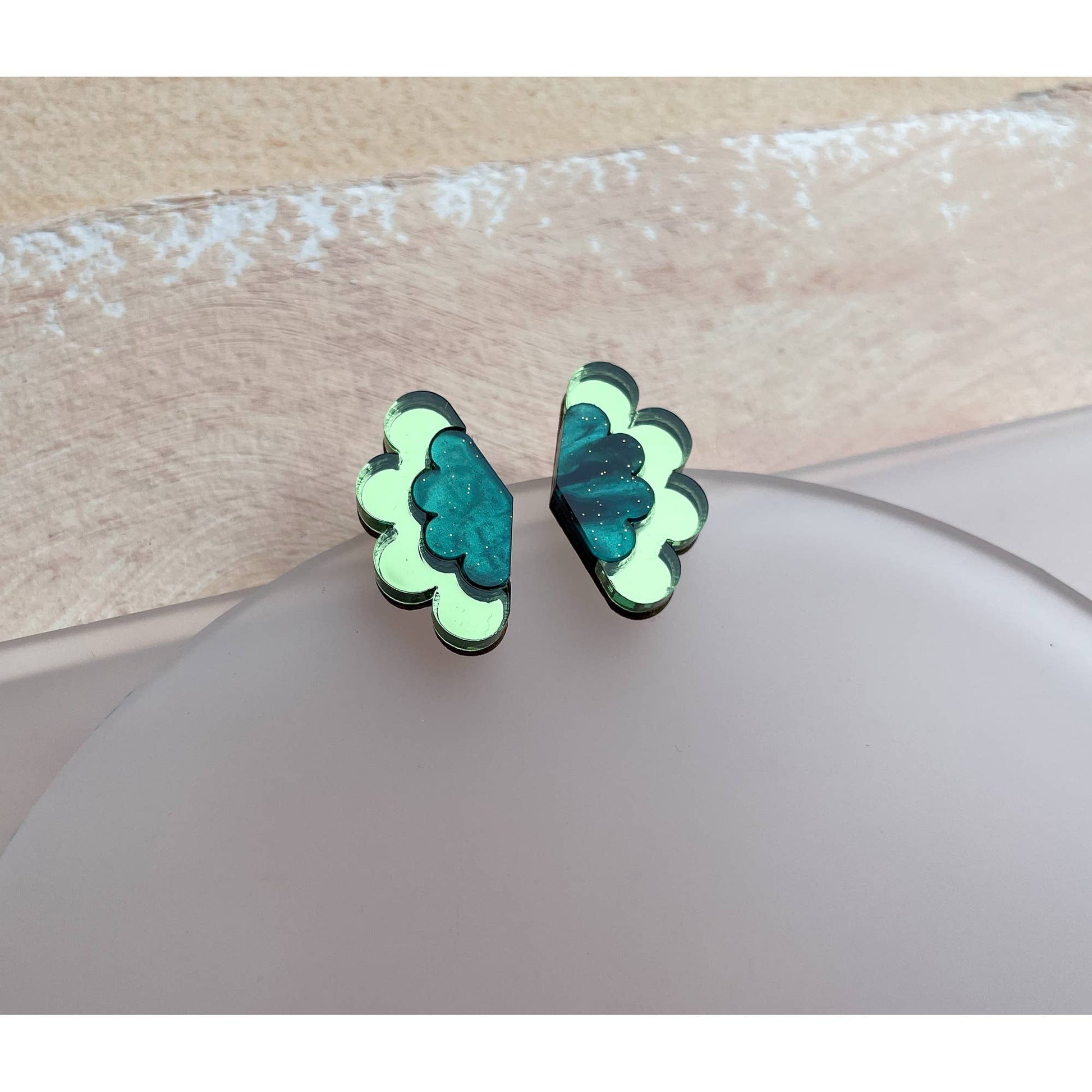 Pair of green butterfly-shaped earrings on a beige surface