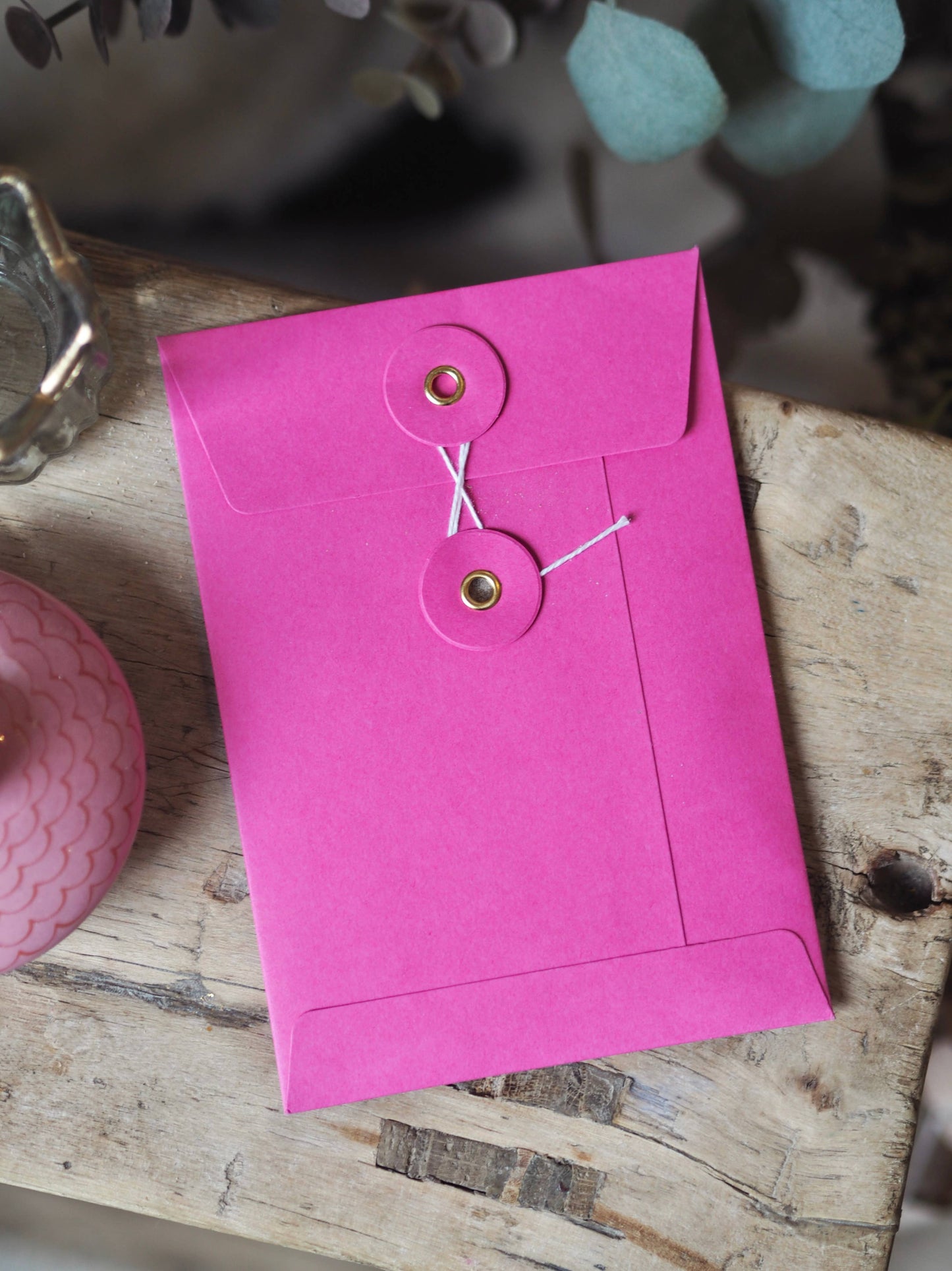 Pink envelope with a tag on a wooden surface