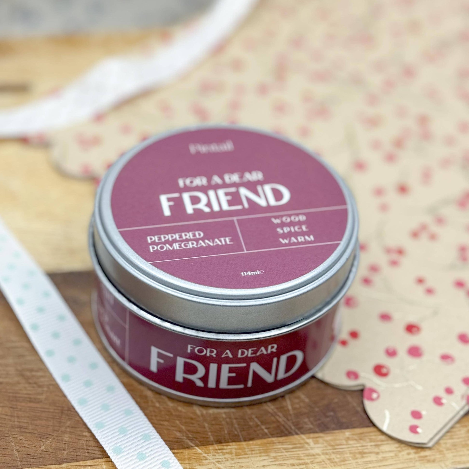 Tin labeled 'For a Dear Friend' on a wooden surface with a polka dot card in the background.