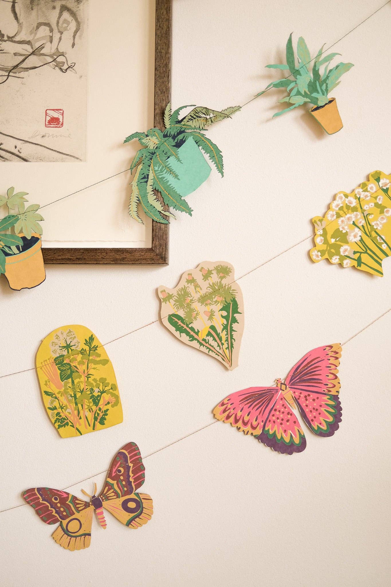 Decorative paper cutouts of plants and butterflies on a tiled wall.