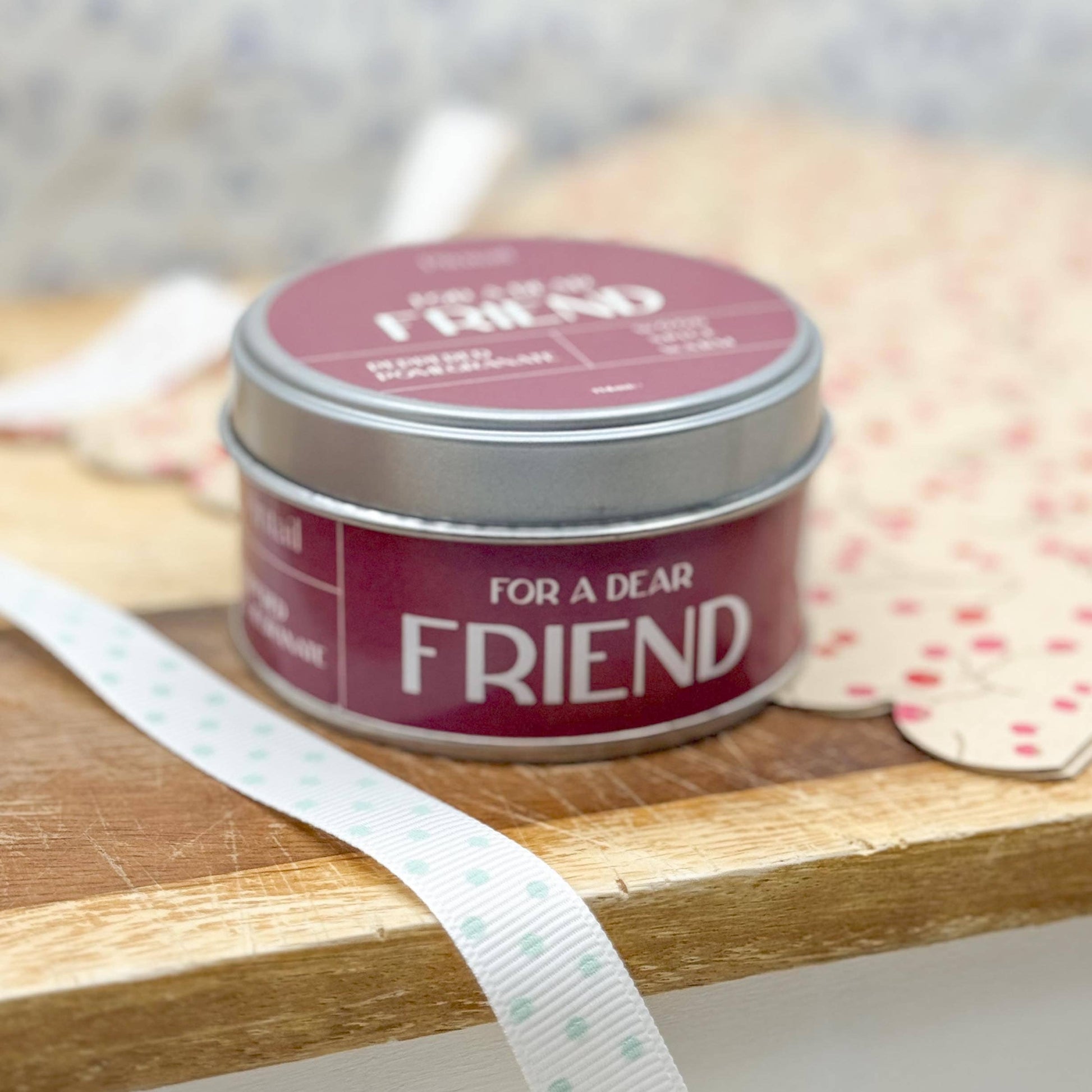 Small tin labeled 'For a Dear Friend' on a wooden surface with a blurred background