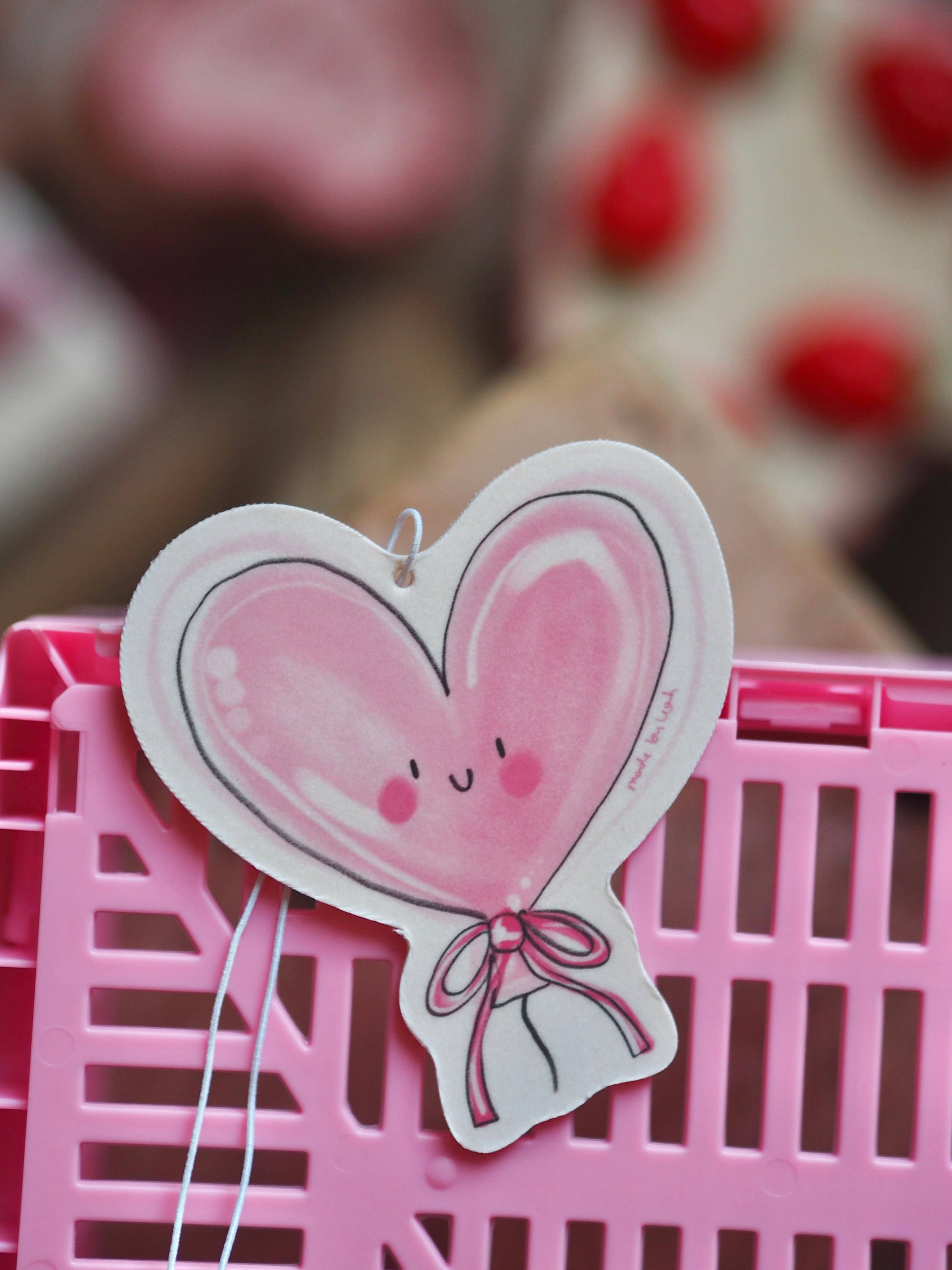 Heart-shaped balloon with a face on a pink background