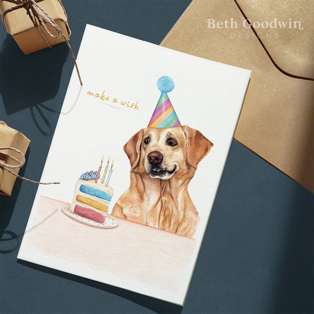 Birthday card with a dog wearing a party hat and birthday cake, on a dark blue surface with brown envelopes.