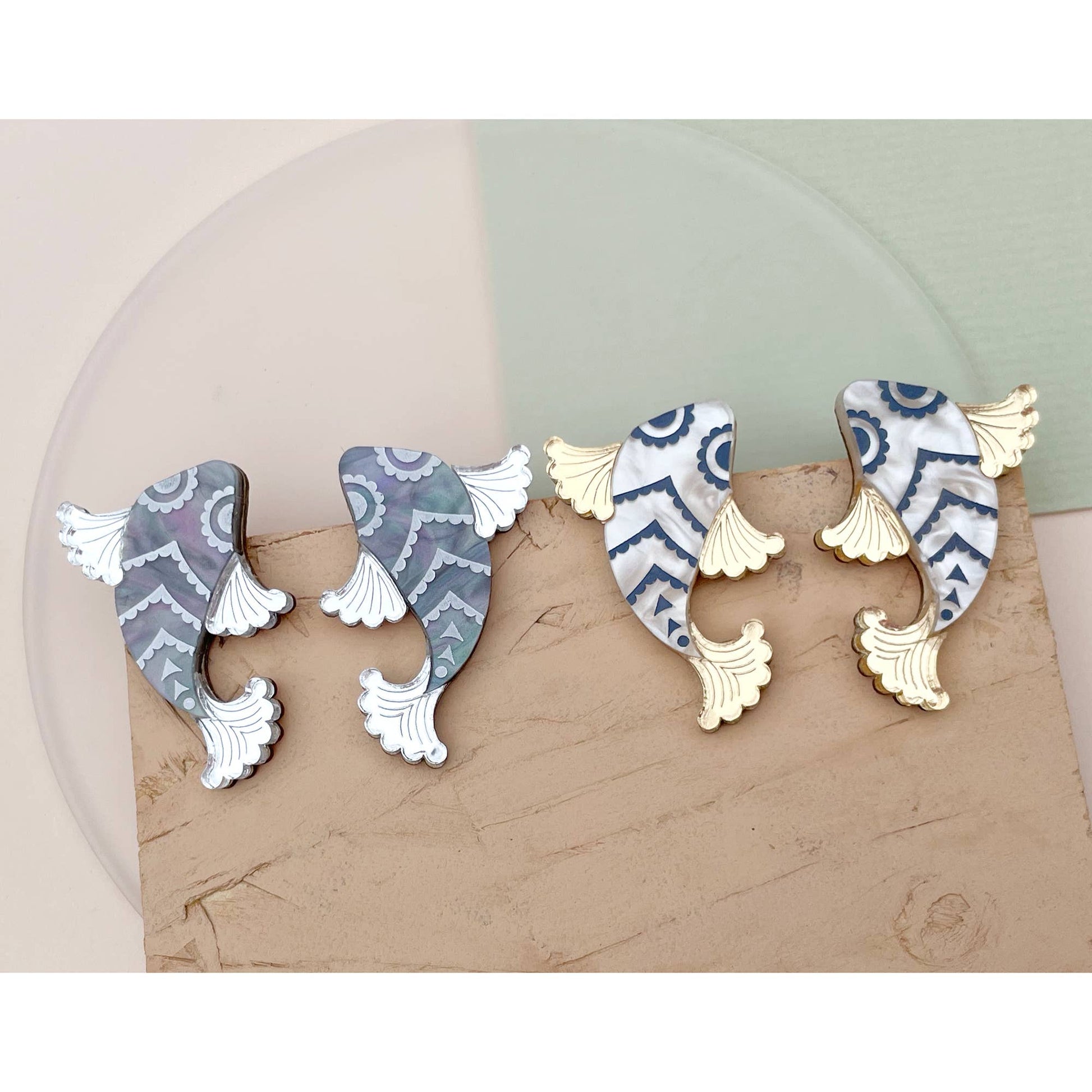 Pair of earrings with geometric patterns on a beige surface