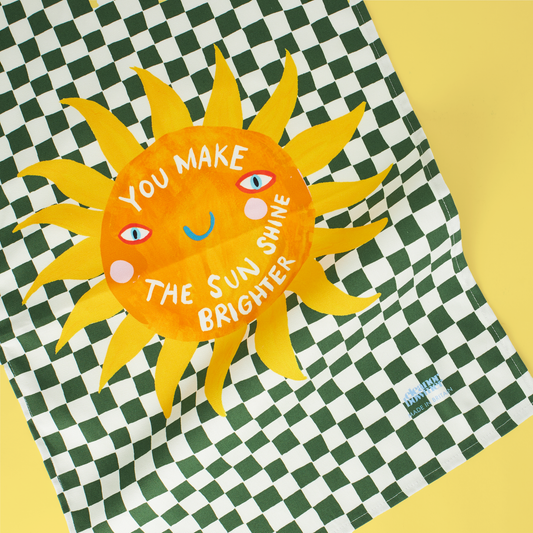 Sun-shaped poster with motivational quote on a green and white checkered background