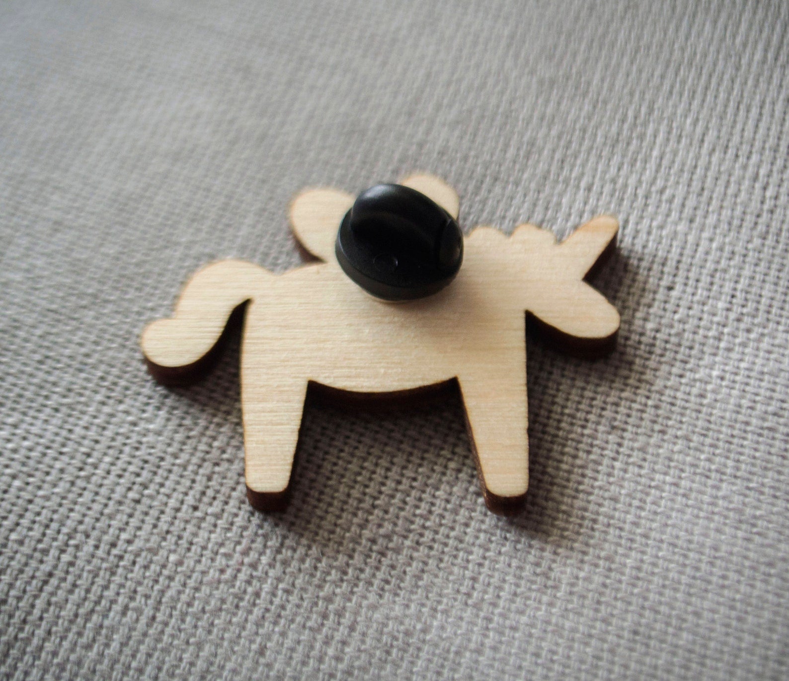 The back of a brightly painted wooden brooch of a unicorn.