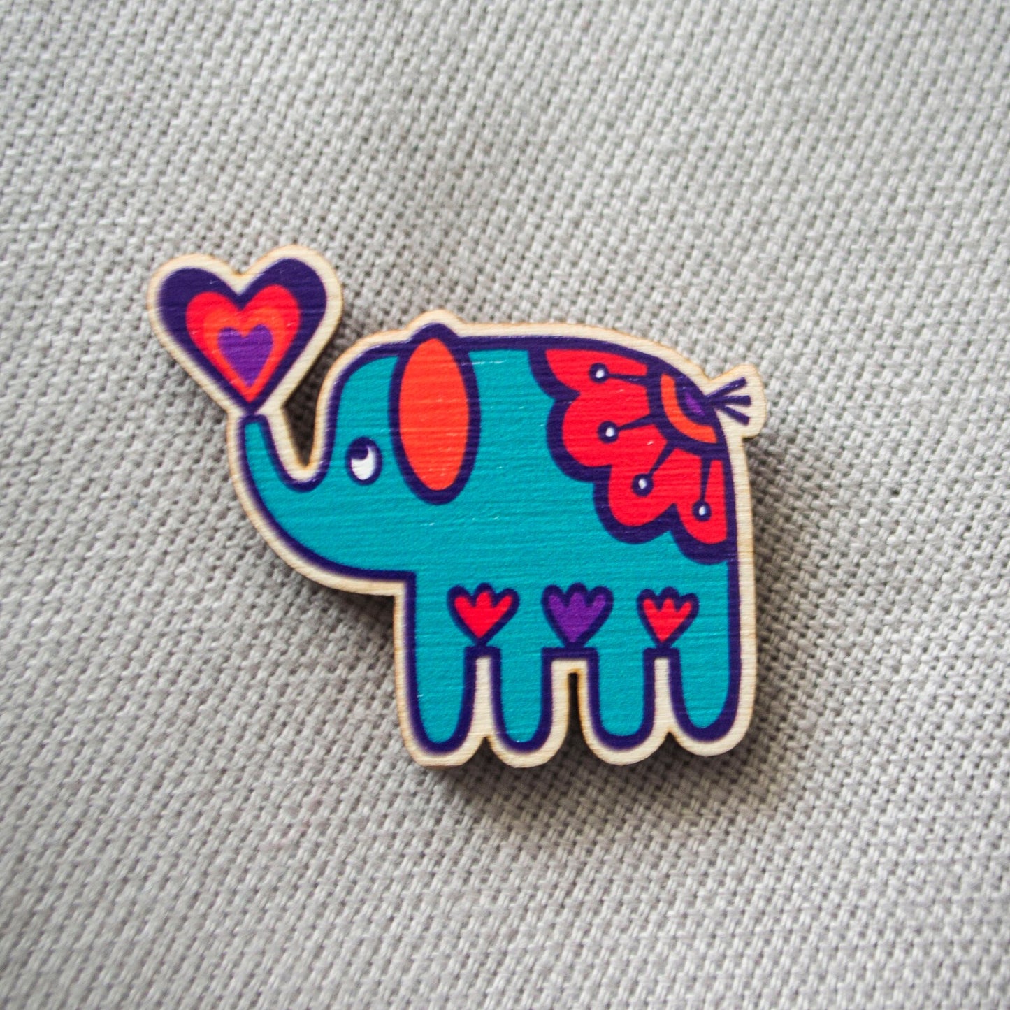 A brightly painted wooden brooch of an art deco inspired blue elephant.