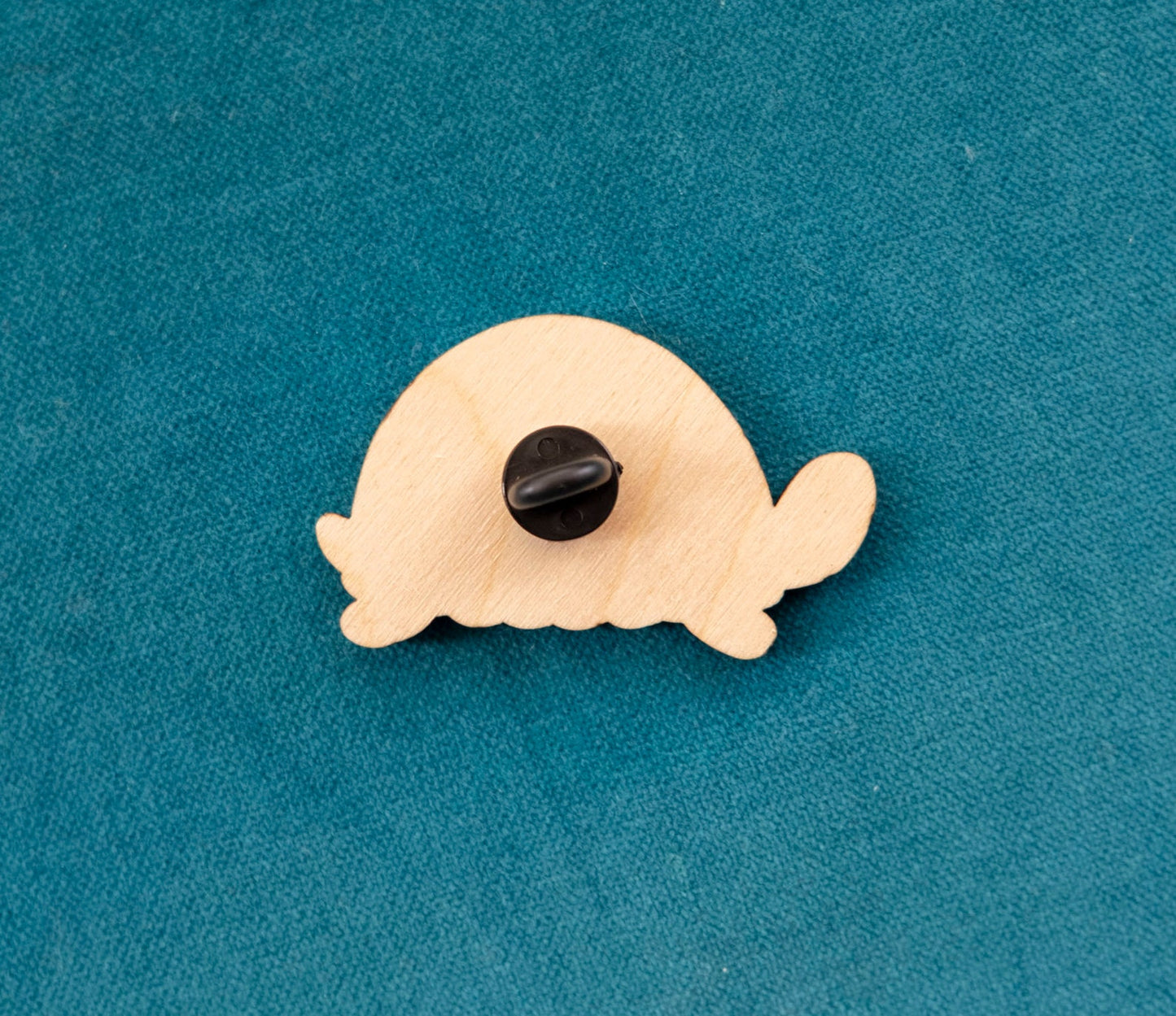 The back of a brightly painted wooden brooch of an art deco inspired tortoise with windows and a door on its shell.