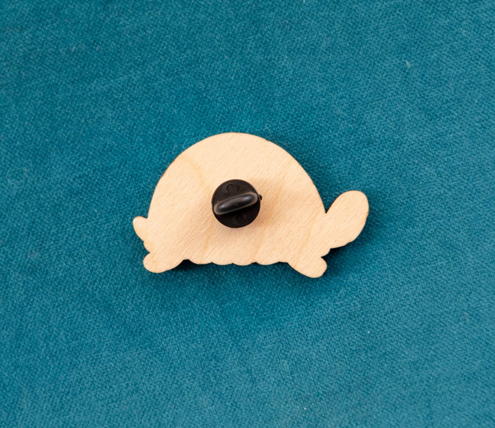 The back of a brightly painted wooden brooch of an art deco inspired tortoise with windows and a door on its shell.