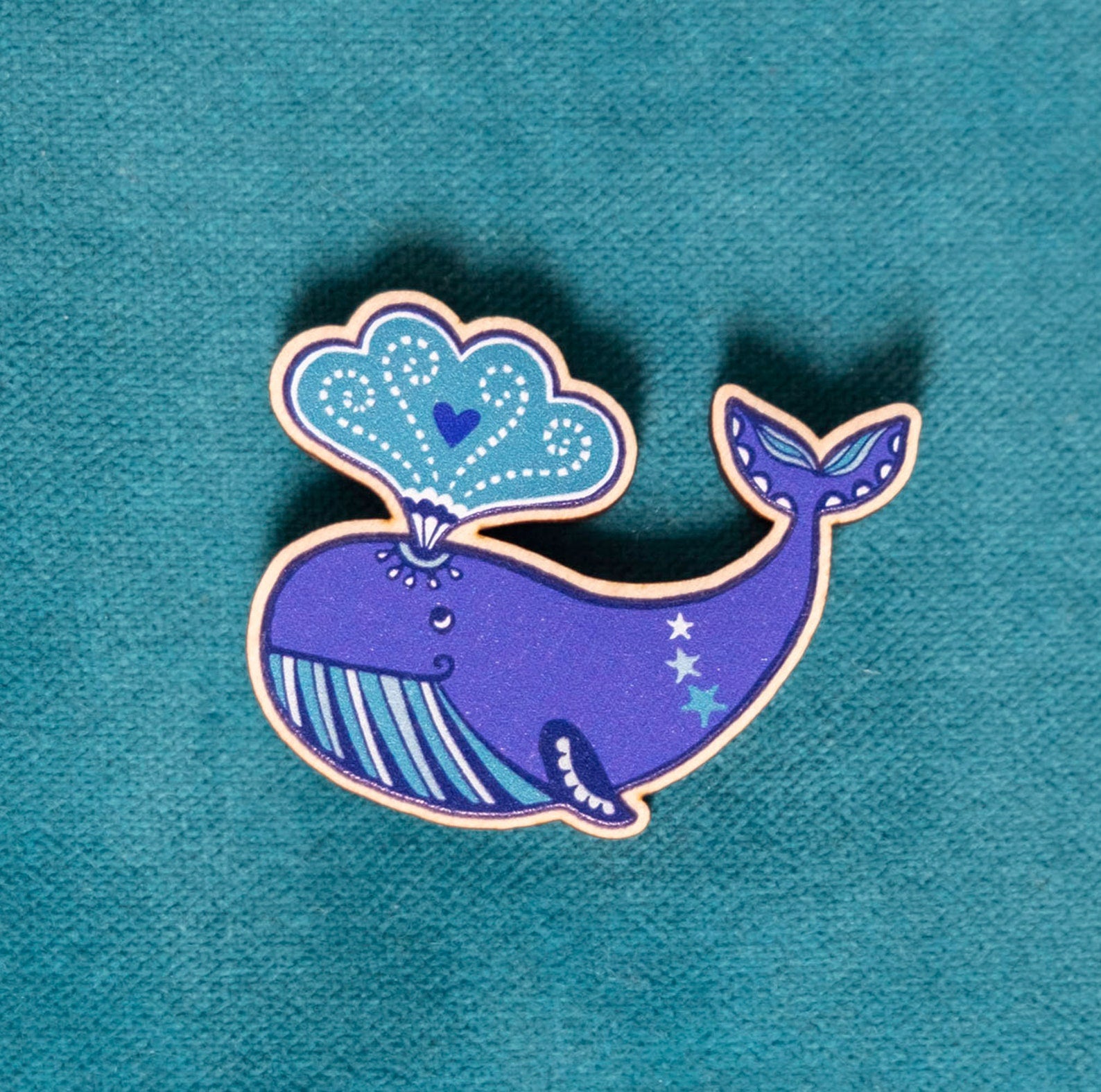 A wooden brooch of a cartoon whale.