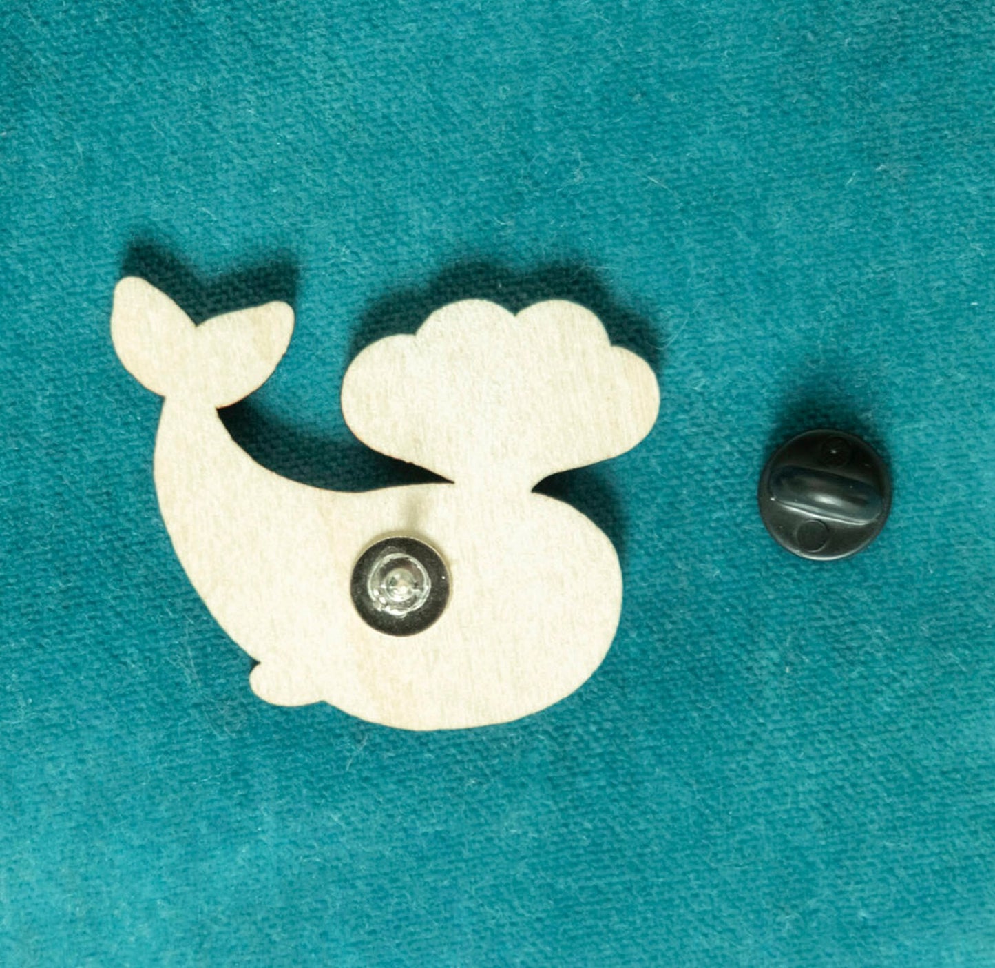 The back of a wooden brooch of a cartoon whale.