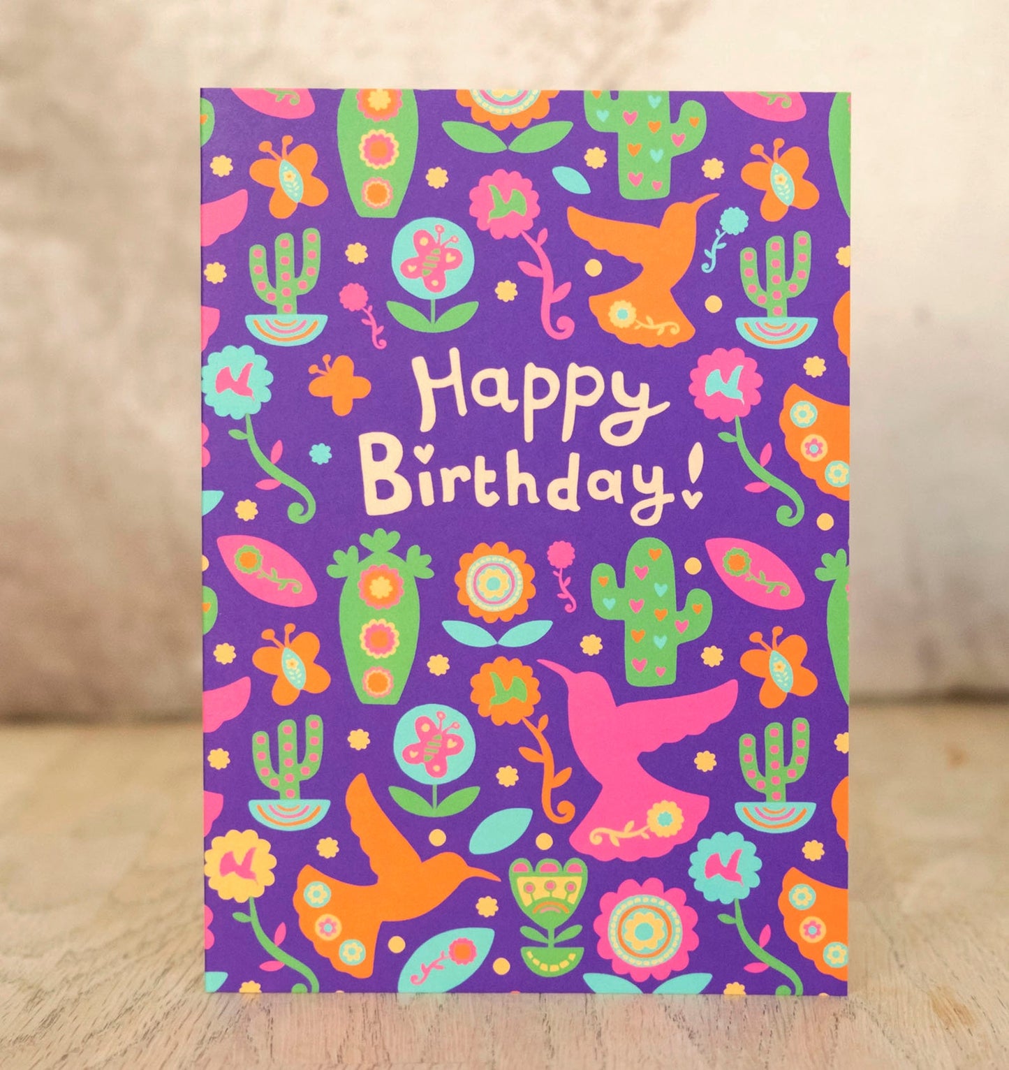 A purple card with a bird and cactus pattern. In the middle it says "Happy Birthday!"