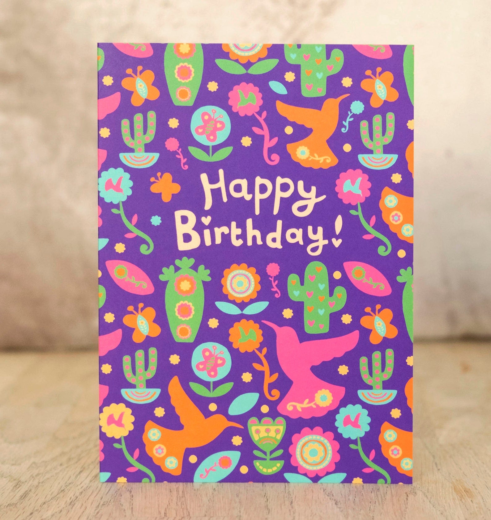 A purple card with a bird and cactus pattern. In the middle it says "Happy Birthday!"