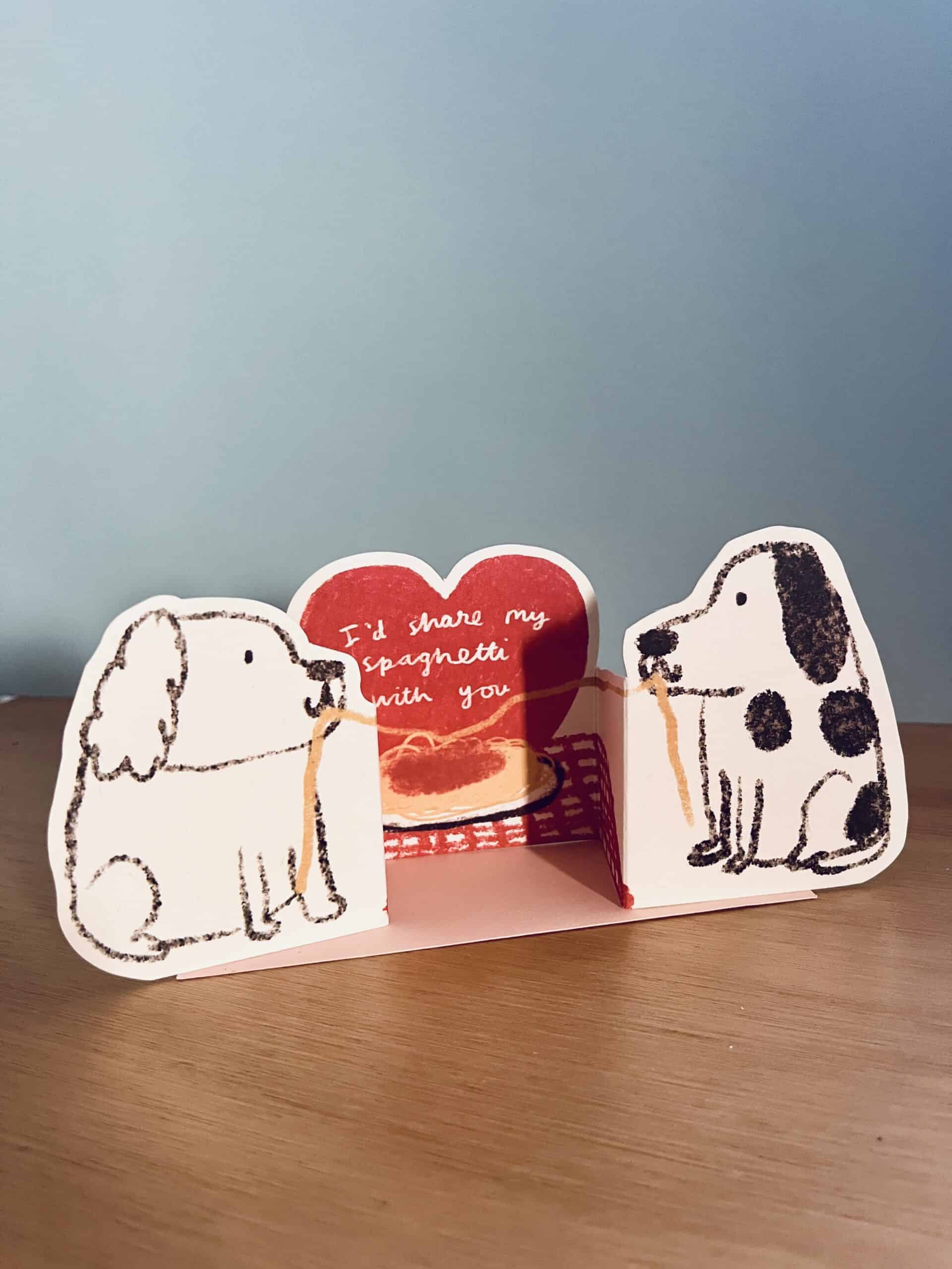 Bookend set with dog illustrations and a heart-shaped card on a wooden surface.
