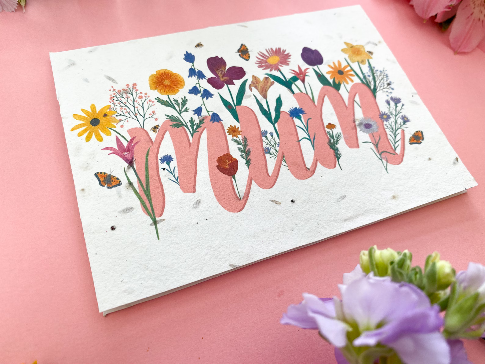 A card with wildflower seeds enbedded in the paper, with a beautiful floral design with the words mum, a lovely mothers day card