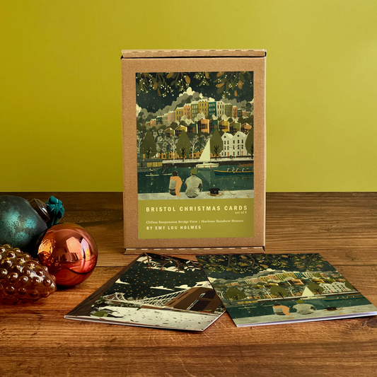 Box of Bristol Christmas cards on a wooden surface with festive decorations.