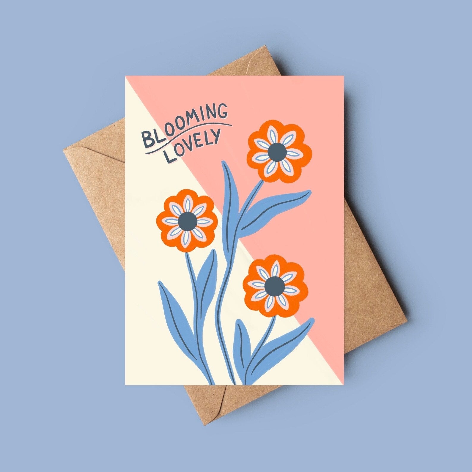 Greeting card with floral design and 'Blooming Lovely' text on a pink background, with a brown envelope.