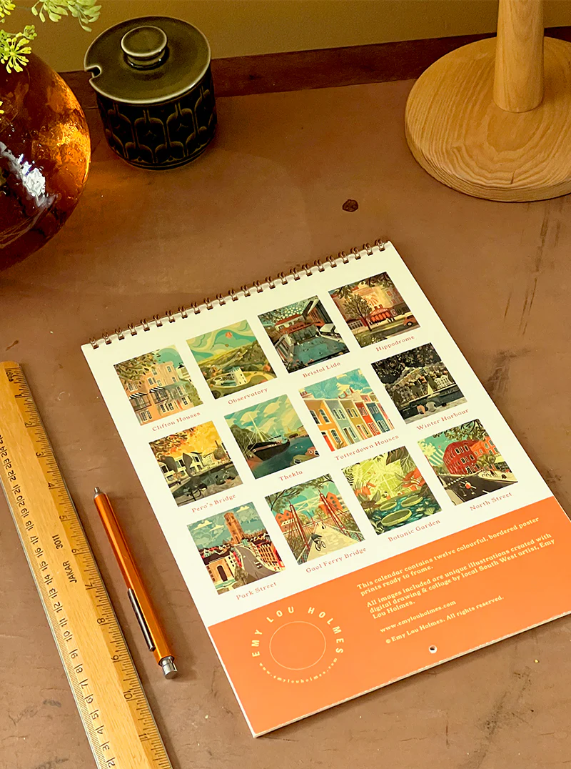 Calendar with scenic designs on a wooden surface with a ruler and pen.