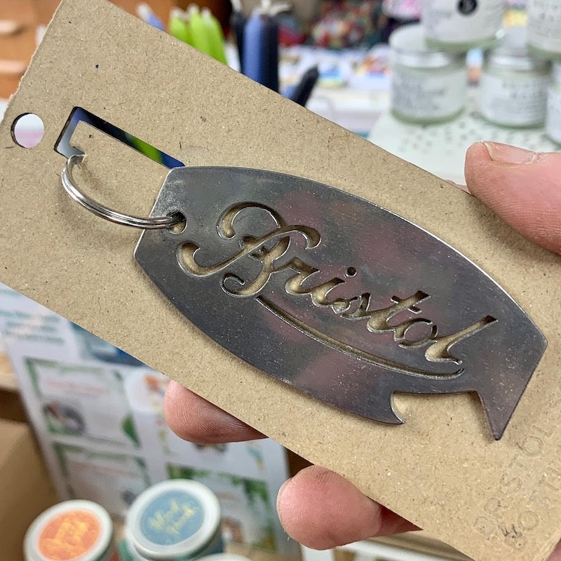 A metal keyring bottle opener with the Bristol Scroll lazered in the centre.