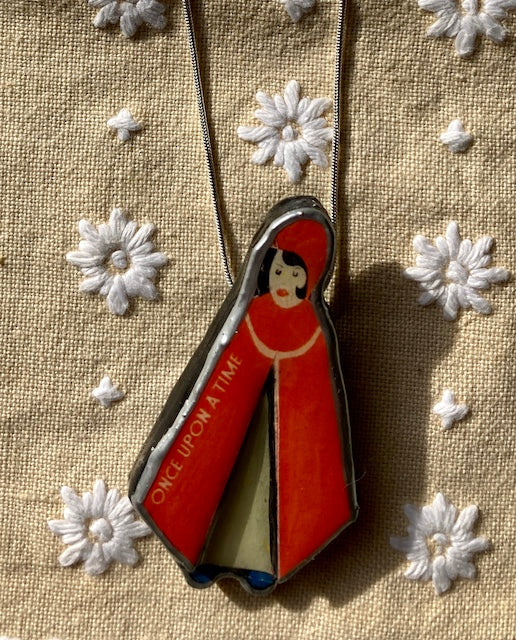 Handmade in Cardiff by layering paper, metal and resin.  This pendant is of Little Red Riding Hood with the words Once upon a time on her cape.