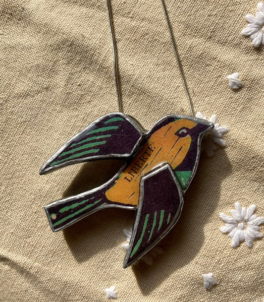 Handmade Pendant by Elymental a Cardiff based artist.  Layered papers and metal and finished off with layers or resin.  The  chain is 18 inch silver plated.  The text across the flying birds body ready Liberte
