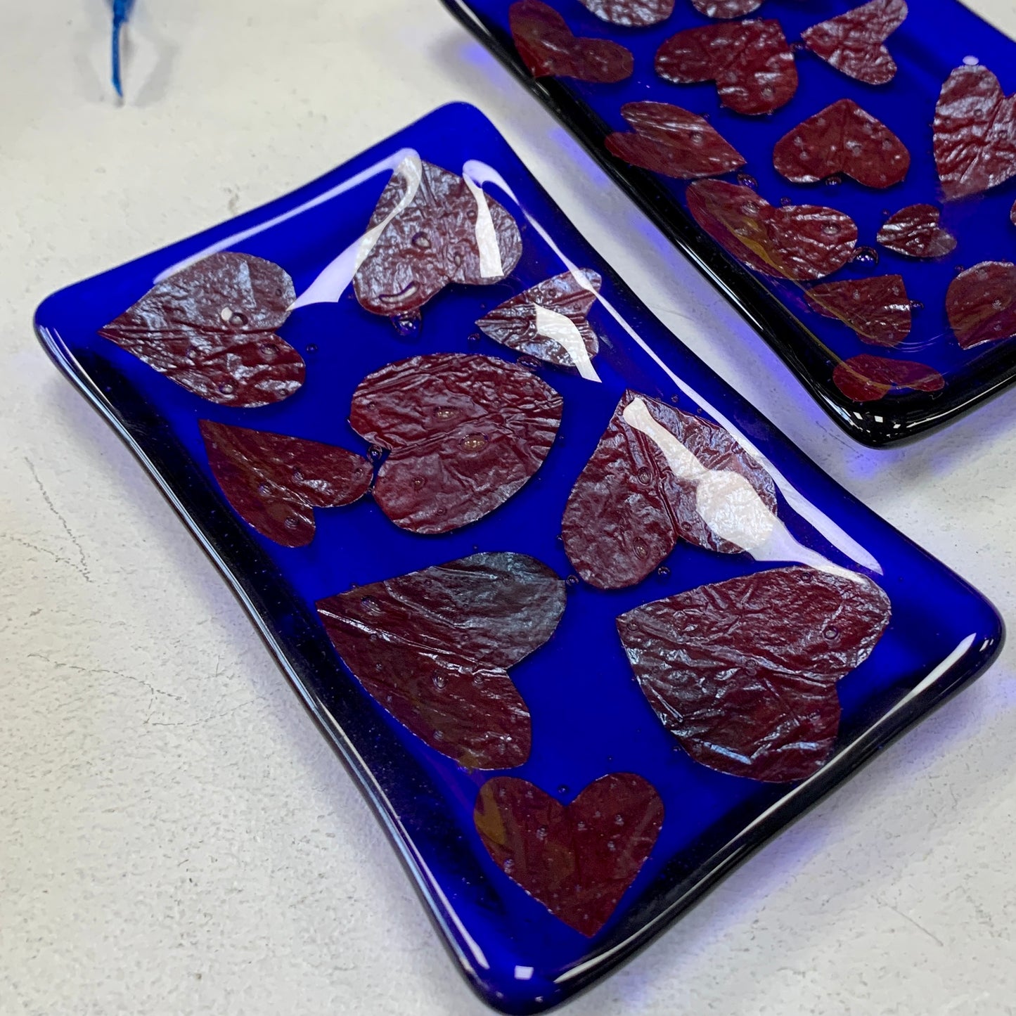 Bristol Blue Glass fused trinket dish or soap dish with Rusty red hearts fused between the glass. Handmade in Bristol.
