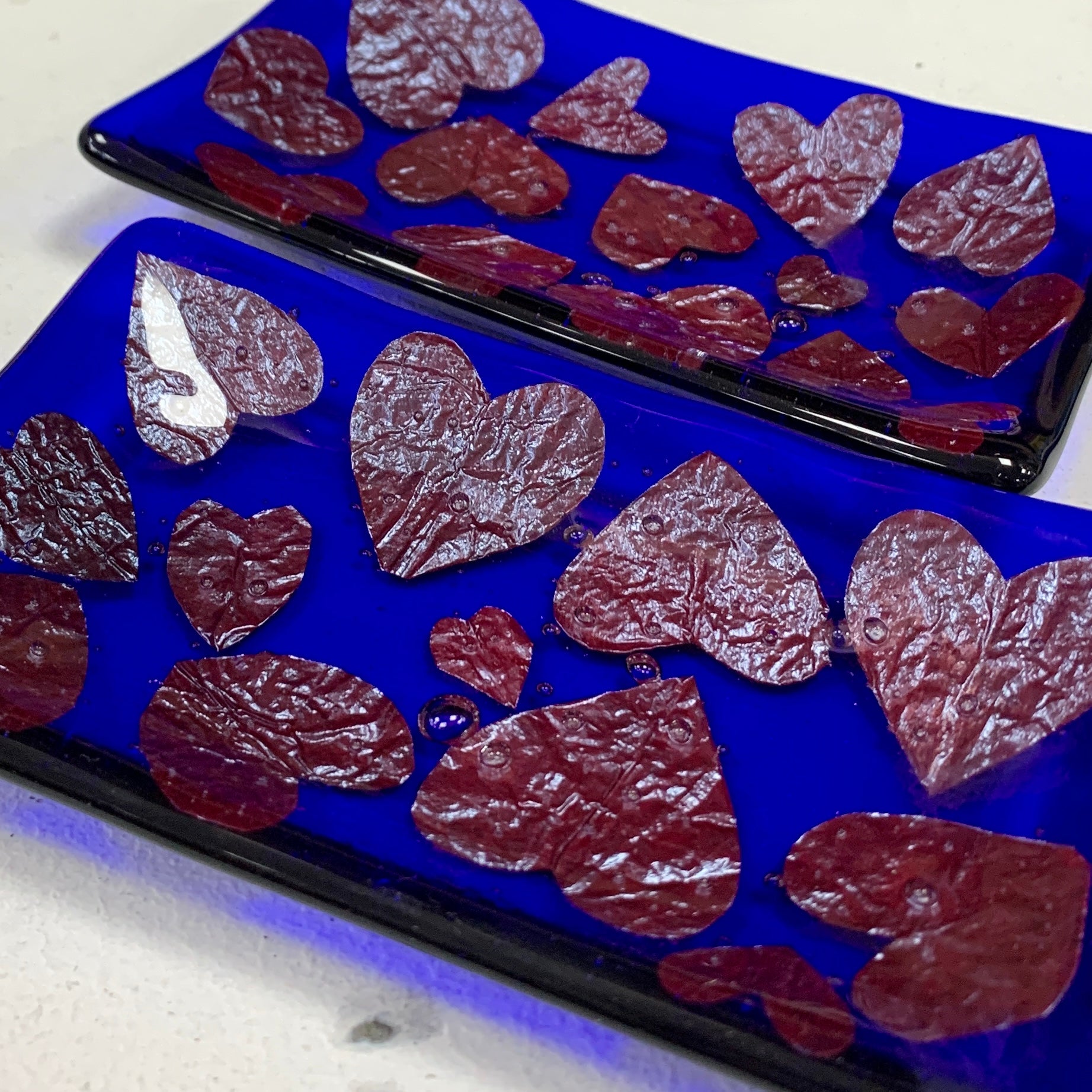 Bristol Blue Glass fused trinket dish or soap dish with Rusty red hearts fused between the glass. Handmade in Bristol.
