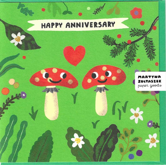 Two red spotted mushrooms with smiley faces on green background with leaves and flowers