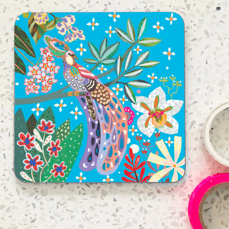 Coaster with colouful illustration of a peacock with bright blue background