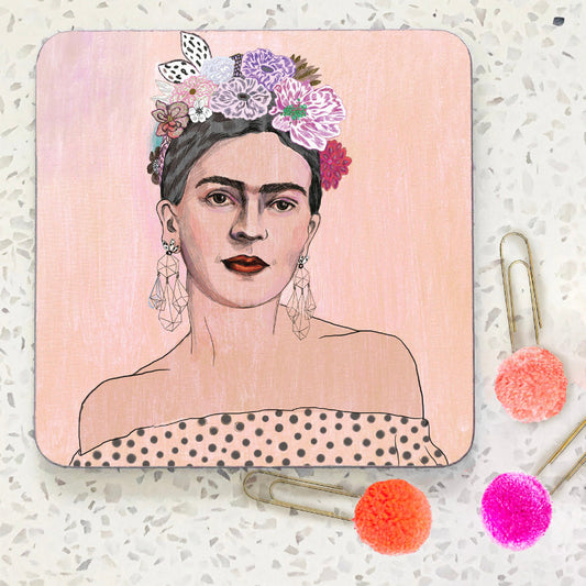 Coaster with hand illustrated portrait of Frida Kahlo in shoulderless dress and flowers in her hair. Background is pale pink.