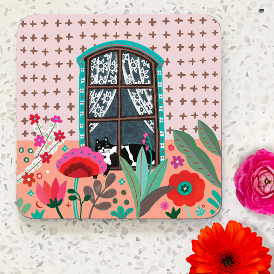 Coaster with black and white cat in a window with pink flowers in foreground