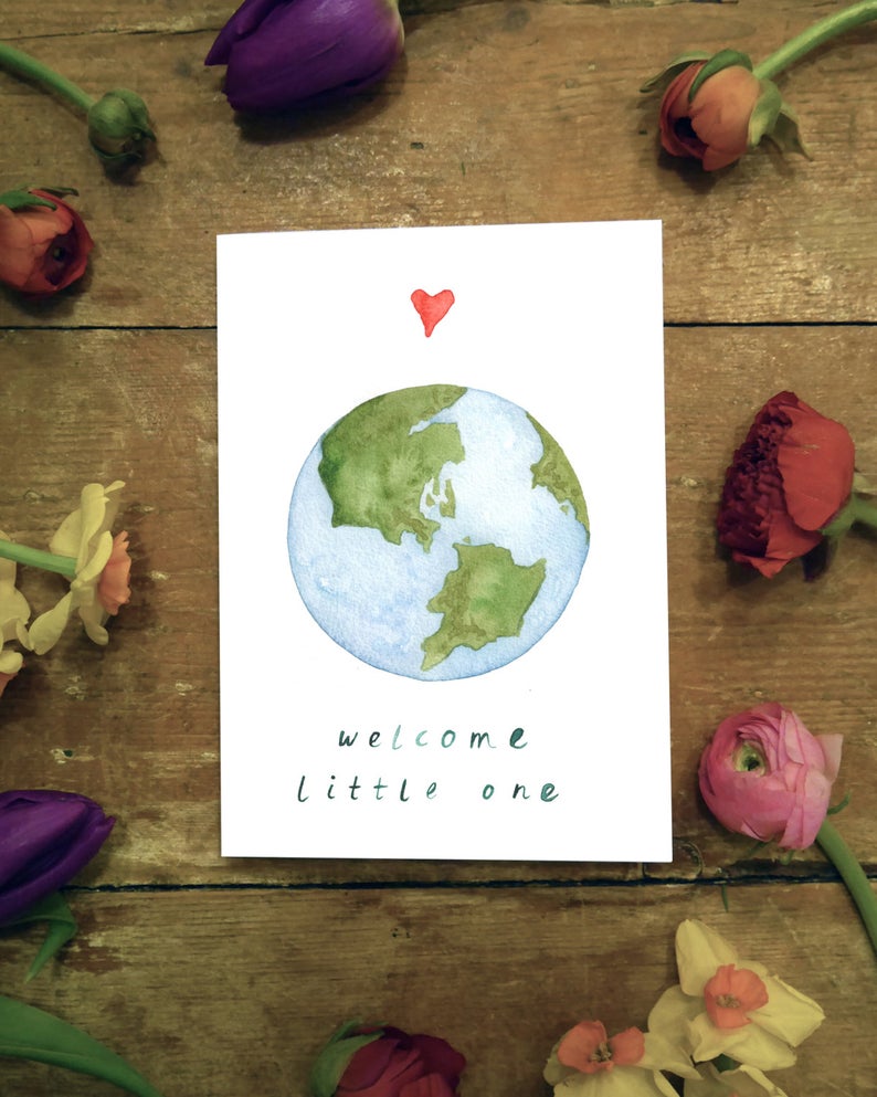 watercolour greetings card with the world and a heart and the words ''welcome little one'' 