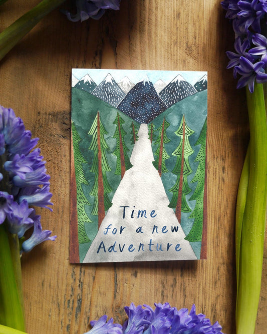 Watercolour greetings card with mountains trees and a road with the words 'Time for an adventure' 