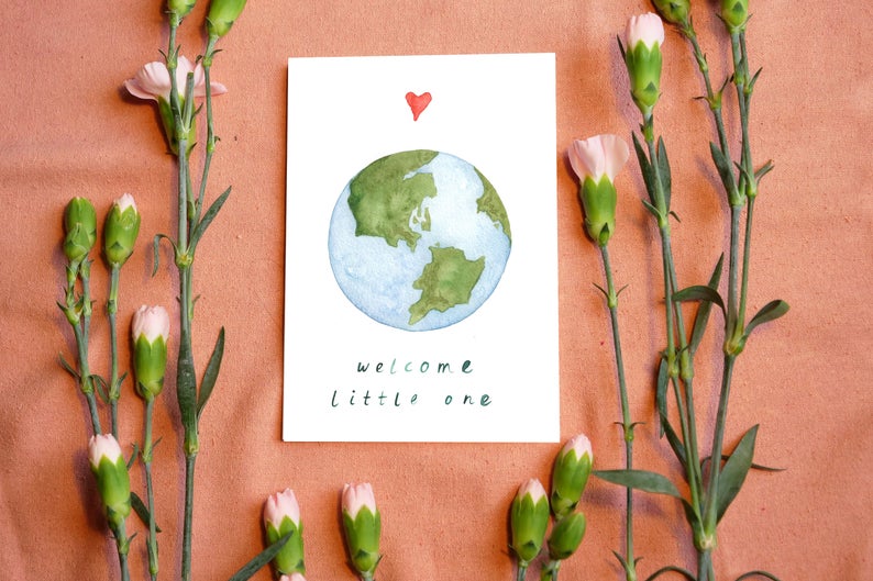 watercolour greetings card with the world and a heart and the words ''welcome little one'' 