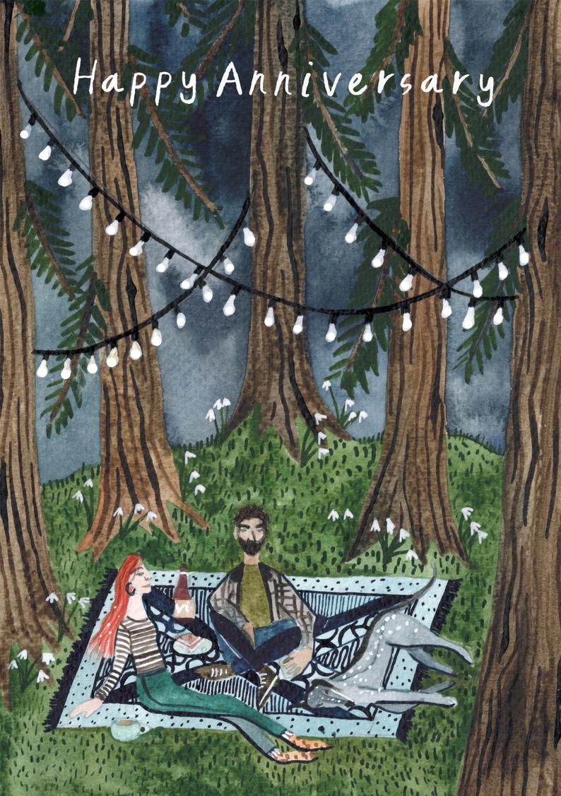 watercolour greetings card with couple and dog picnicing in a woods with lights in the trees and the words ''happy anniversary''