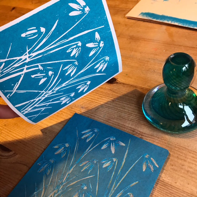 Lino print of snowdrops in turquoise card.