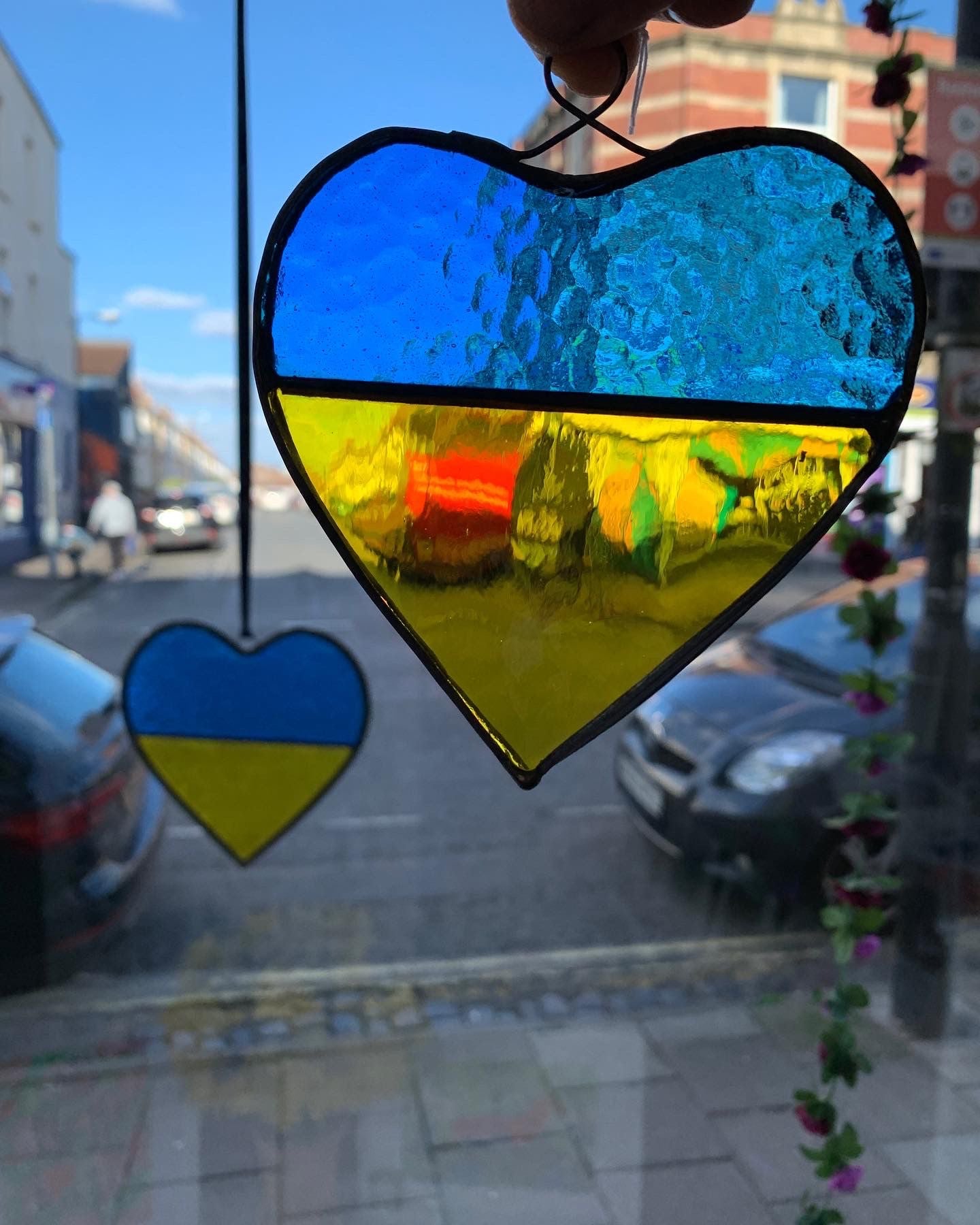 A glass heart in the colours of the Ukrainian flag - blue and yellow - made in support of the Ukrainian people. The profit will be donated to the Red Cross in order to help those forced to leave their homes in times of conflict. Copperfoiled with lead trim. 12cm x 11cm (including loop).