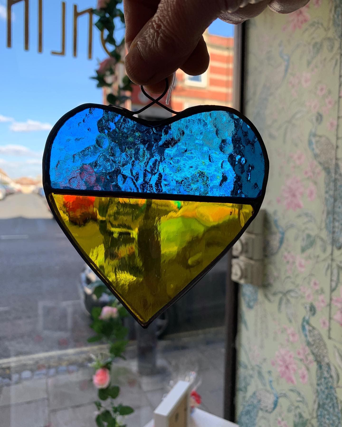A glass heart in the colours of the Ukrainian flag - blue and yellow -  made in support of the Ukrainian people.  The profit will be donated to the Red Cross in order to help those forced to leave their homes in times of conflict.  Copperfoiled with lead trim. 12cm x 11cm (including loop).