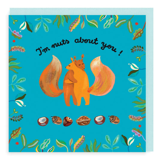 I'm Nuts About You message card. Illustration is two squirrels embracing on bright blue background with assorted nuts and berries