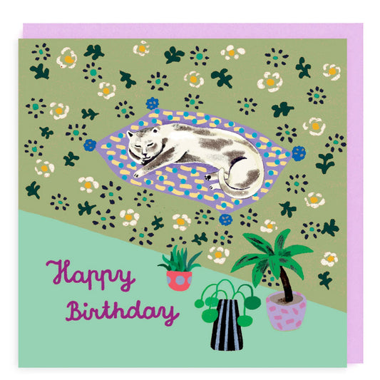 Happy Birthday card with sleeping cat on blanket. Green background with flowers